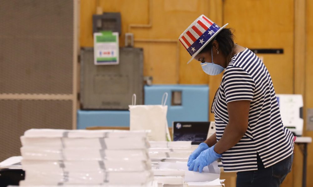 A poll worker with a face mask sorts election materials in a polling station in Wisconsin during the COVID-19 pandemic.