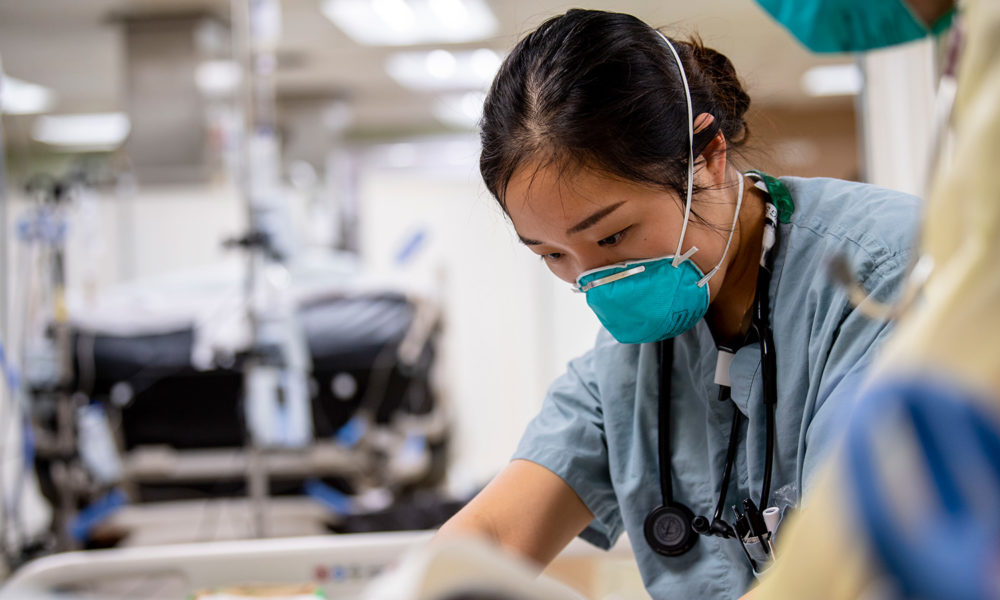 A Navy officer treats a patient in an intensive care unit.