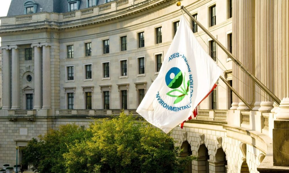 the exterior of the William Jefferson Clinton Federal Building in Washington, DC, from a great height, with the flag of the US Environmental Protection Agency mounted to the side of the building