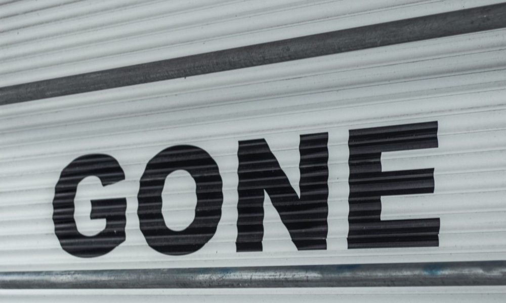 A closed white shutter door like the kind you might find on a storage unit is painted with the word GONE in black capital letters