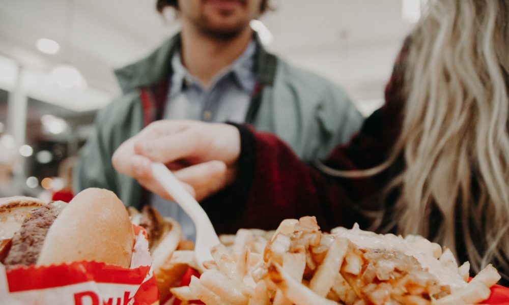 photo of a couple about to eat a trayful of fast-food hamburgers and french fries