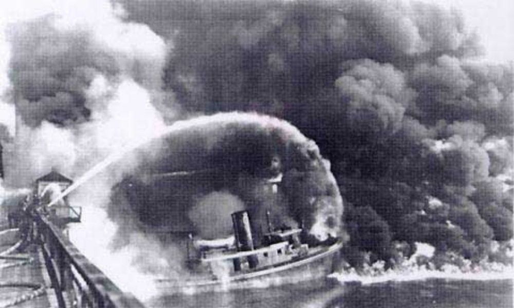 Firefighters stand on a bridge over the Cuyahoga River to spray water on a tugboat as a fire spreads on the water in Cleveland, Ohio, in 1969.