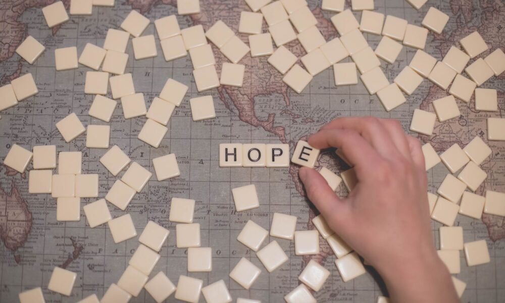 a world map with a bunch of Scrabble tiles on it. the visible letters spell out "HOPE"