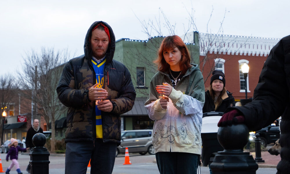 Two people, holding candles, attending a vigil for the war in Ukraine.