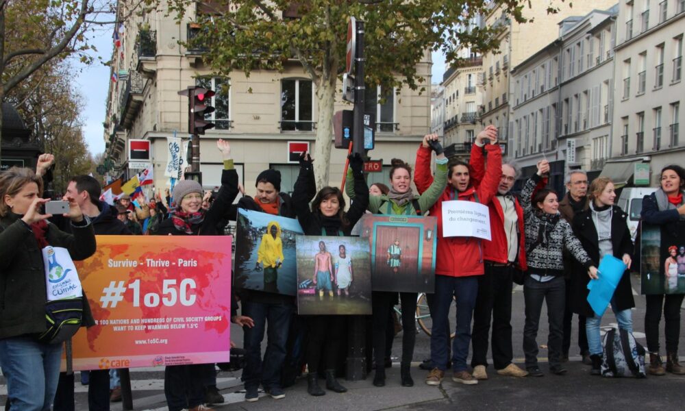 a group of people hold signs in support of climate action and limiting global temperature increases to 1.5 degrees celsius