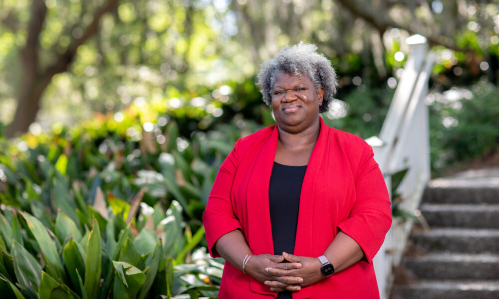 photo of Dr. Jennie Stephens, smiling at the camera, standing at the base of some stairs with woods in the background