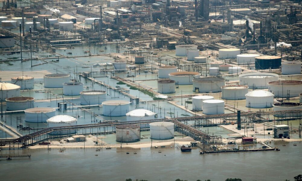 An industrial area near Houston, TX, with large storage tanks and scaffolding everywhere, is submerged by floodwaters from Hurricane Harvey in 2017.