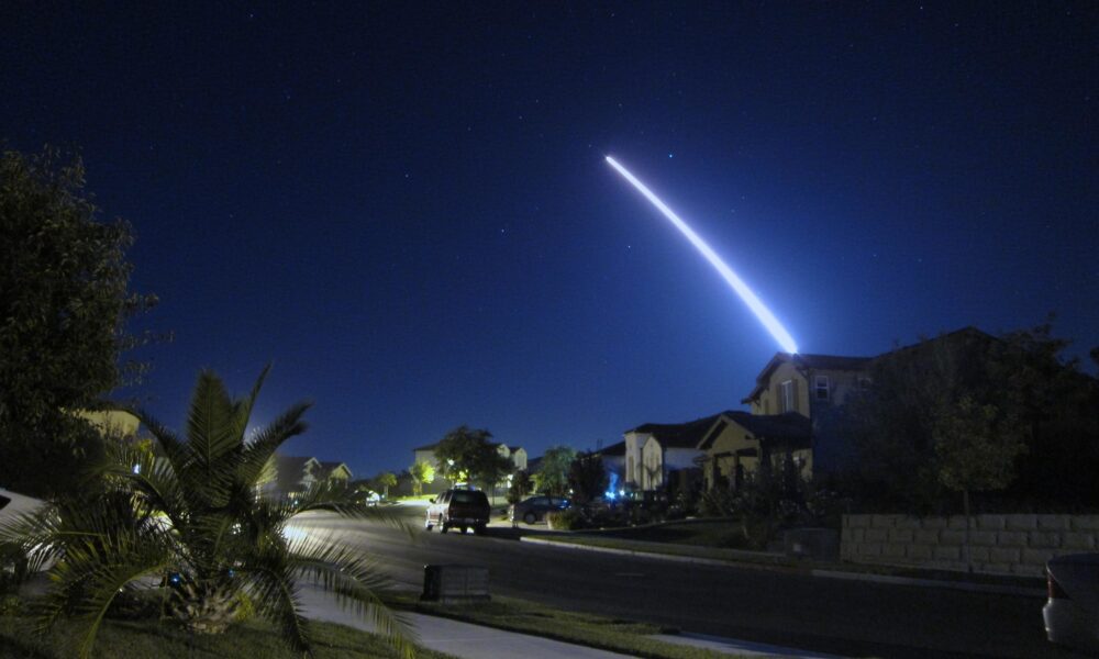 photo of a Minuteman missile launched from Vandenberg Air Force Base in California streaking across the night sky over a suburban neighborhood