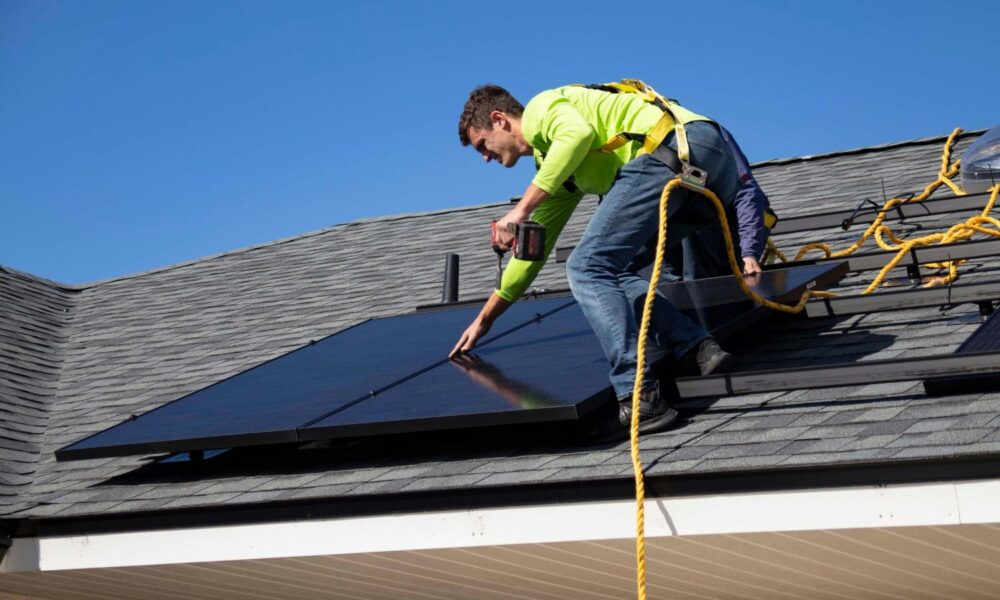 A man installing a solar panel on a rooftop.