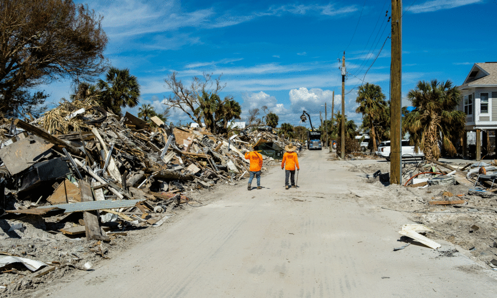 Cleanup workers walk along debris on Ft. Myers Beach, FL.