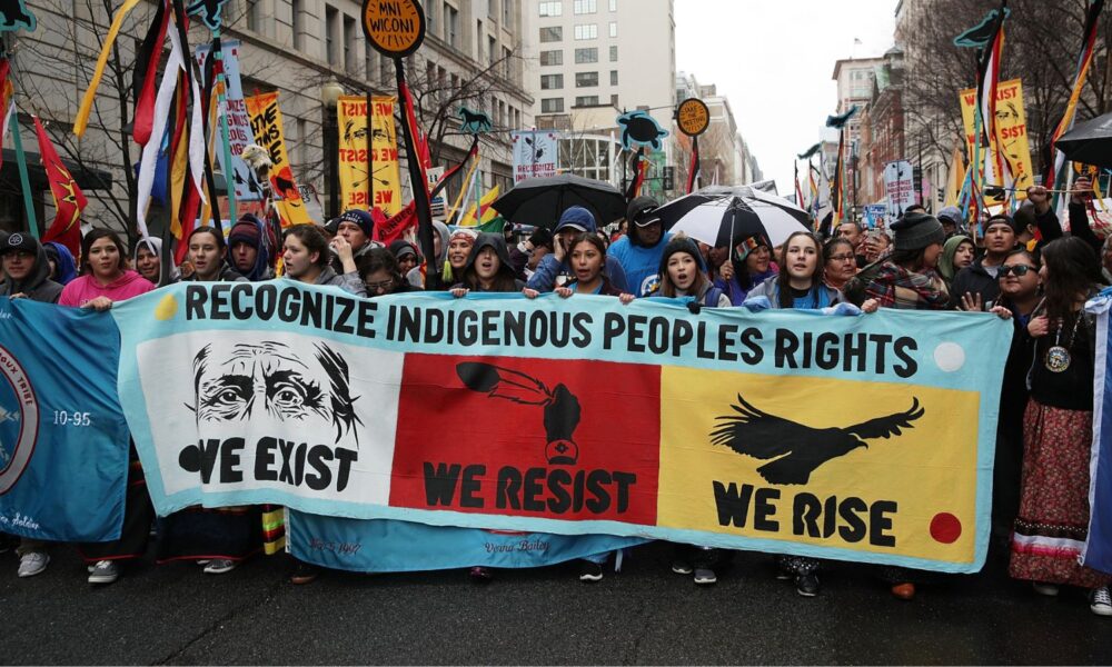 Activists hold a sign reading "recognize Indigenous people's rights: we exist, we resist, we rise." They are participating in a protest against the Dakota Access Pipeline March 10, 2017, in Washington, DC.