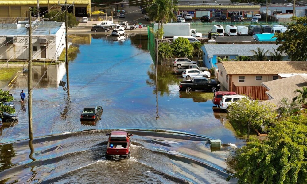 An aerial view of people driving and wading on a flooded residential neighborhood street after heavy rain in December 2024, in Fort Lauderdale, Florida.