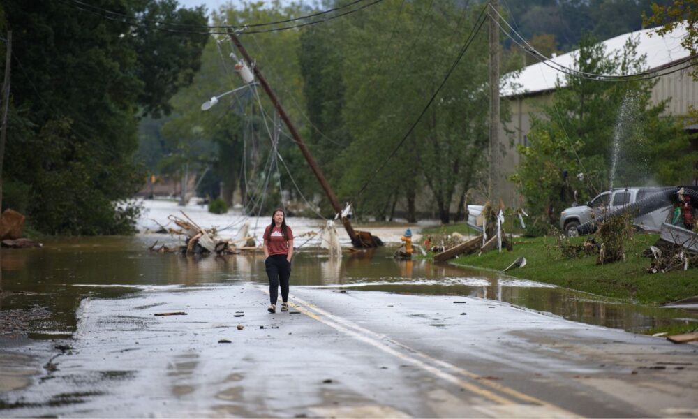 A person walks down a flooded and storm-damaged street in Asheville, North Carolina, post Hurricane Helene.