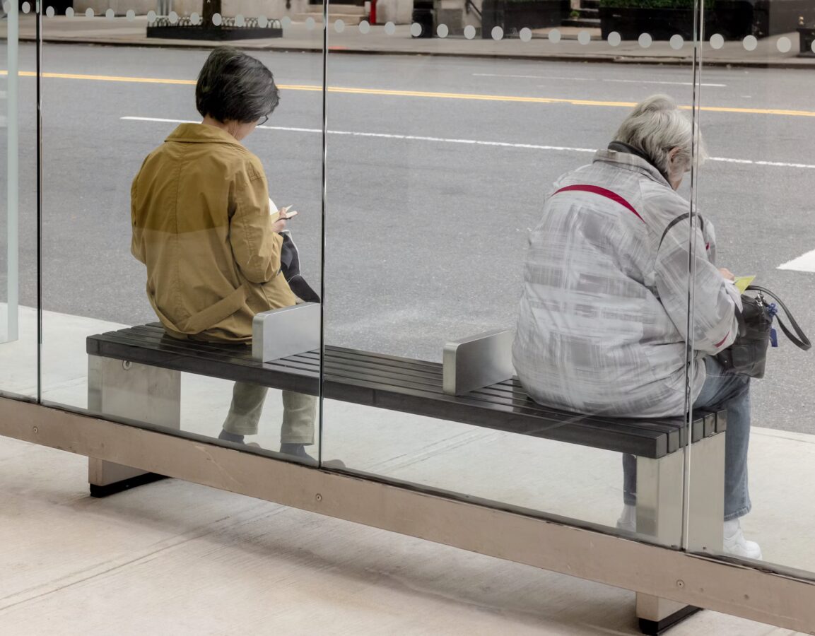 two people sit at a bus stop in New York City