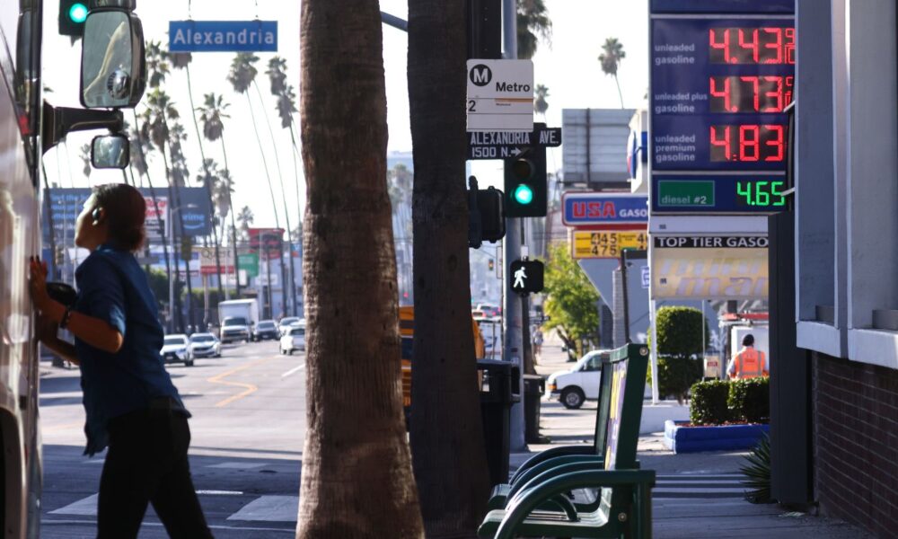 On a busy street in Los Angeles, a gas station displays its prices behind a backdrop of palm trees
