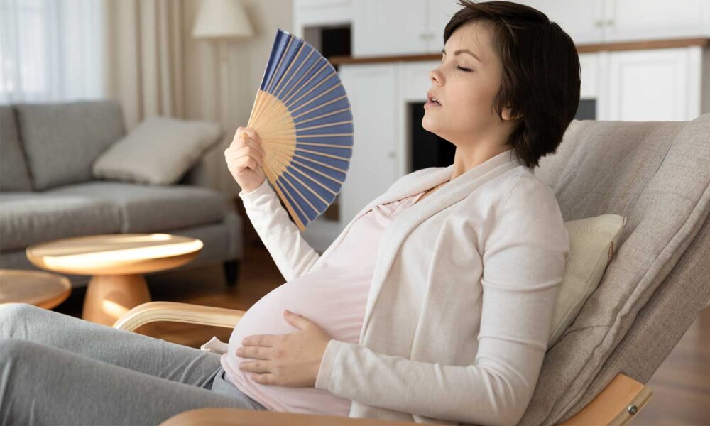 Pregnant woman fans herself.