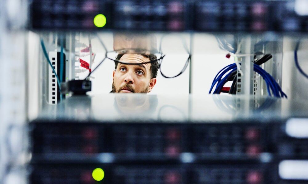 Male IT professional looking through server rack in data center.