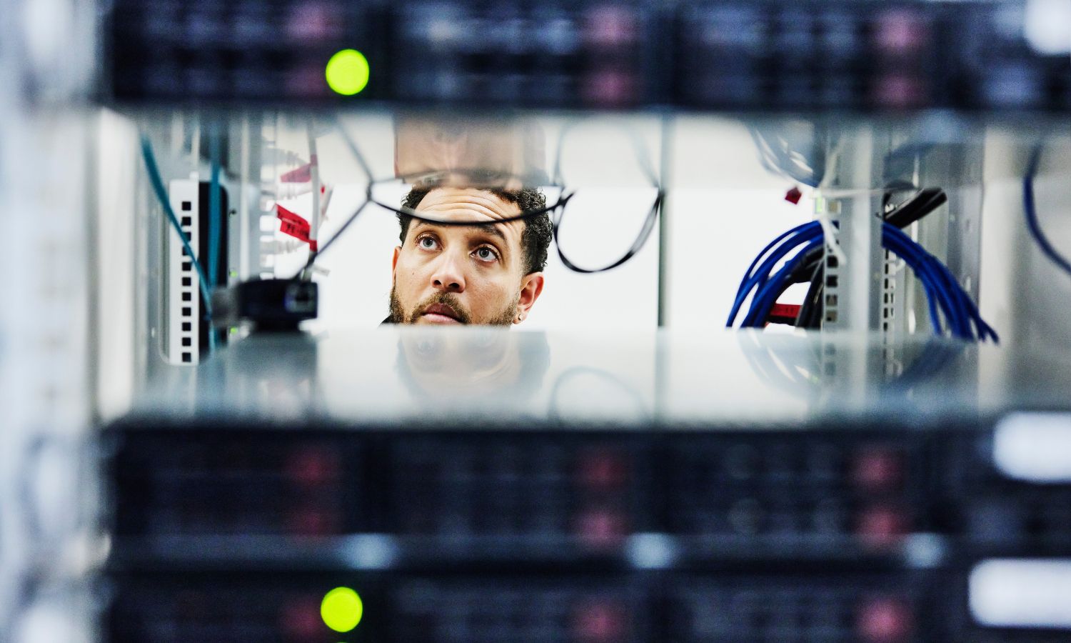 Male IT professional looking through server rack in data center.