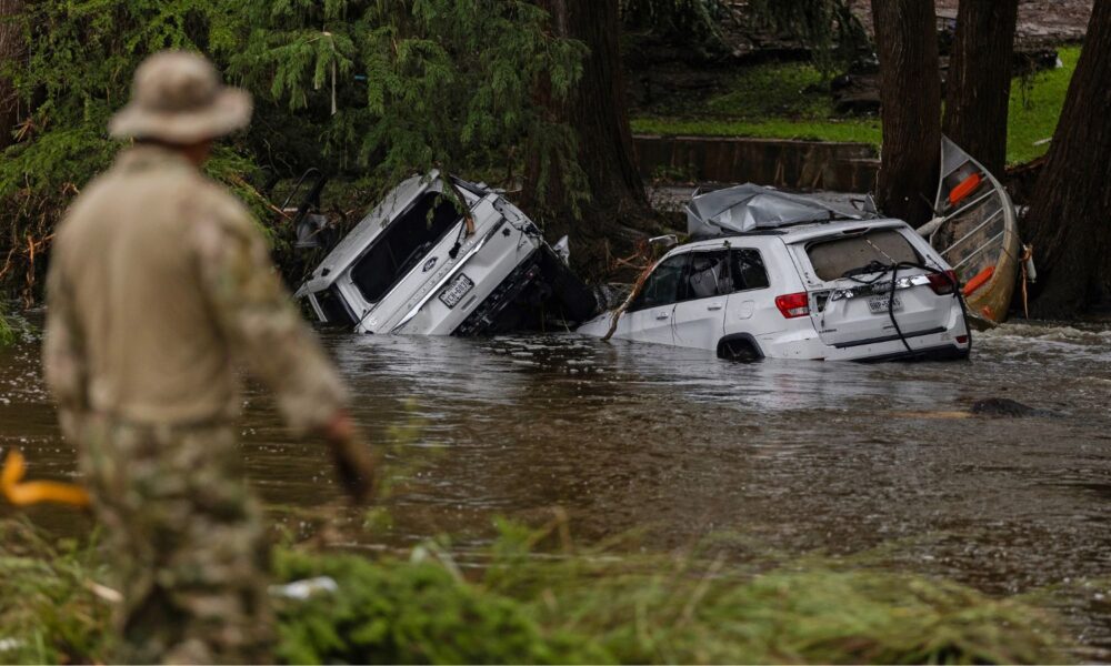 Vehicles sit submerged in floodwater as a search and rescue worker looks through debris for any survivors of the flash flooding in Hunt, Texas, in July 2025.