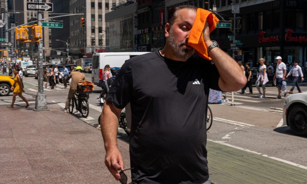 A person wipes sweat from their face with a cloth in Manhattan in July 2025, during a heat wave in which 'feels-like' temperatures were above 100 degrees.
