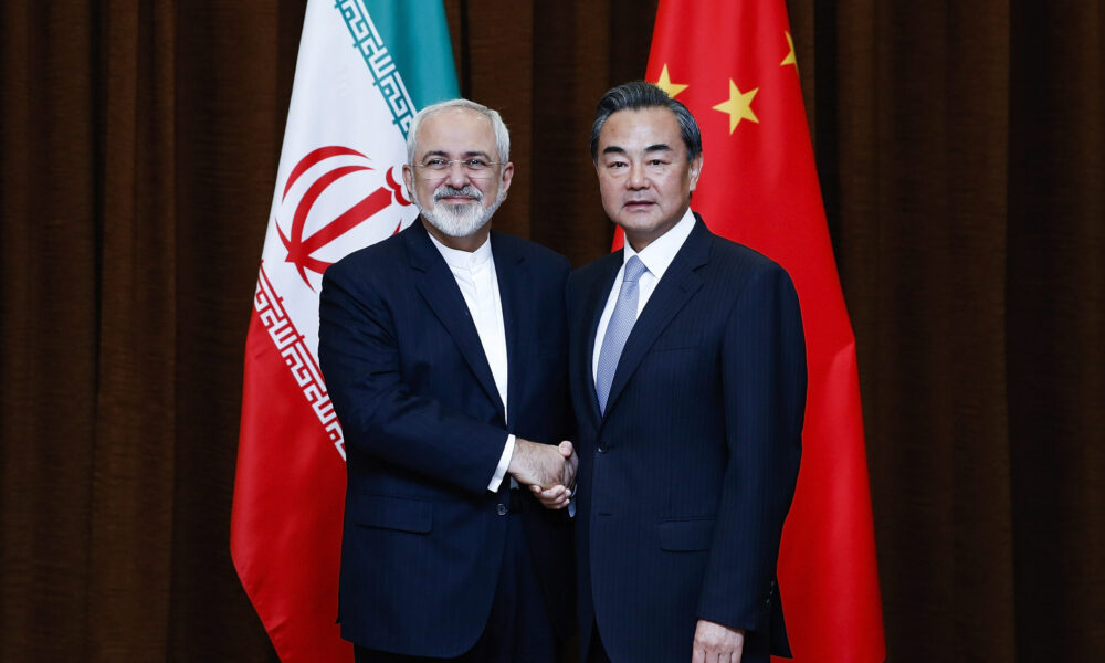 photo of Iranian foreign minister Javad Zarif and Chinese foreign minister Wang Yi shaking hands and posing for the camera in front of their nation's flags during a 2015 meeting