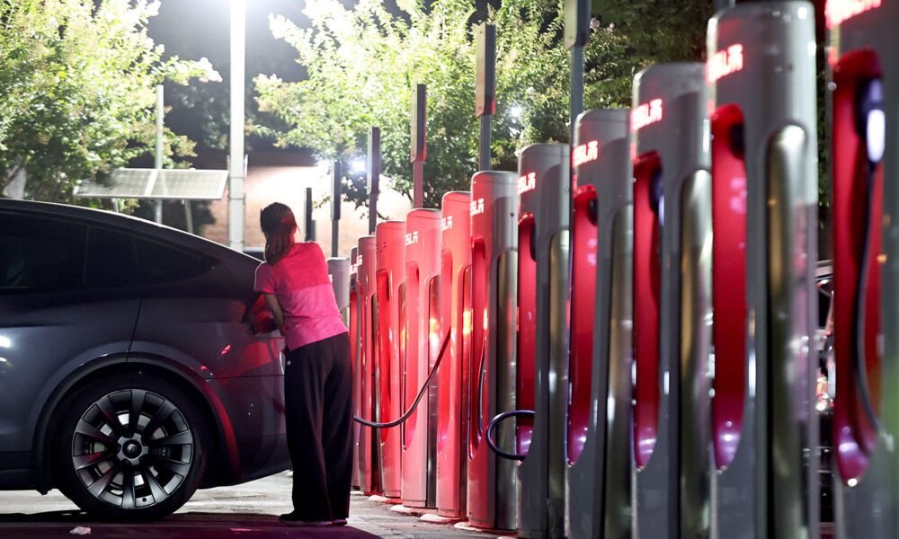 Driver recharges a Tesla EV at a Tesla supercharger station in Pasadena, CA
