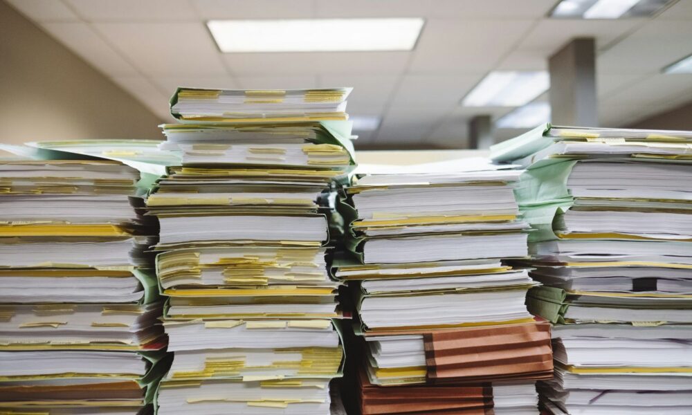 a table with stacks of file folders filled with papers.