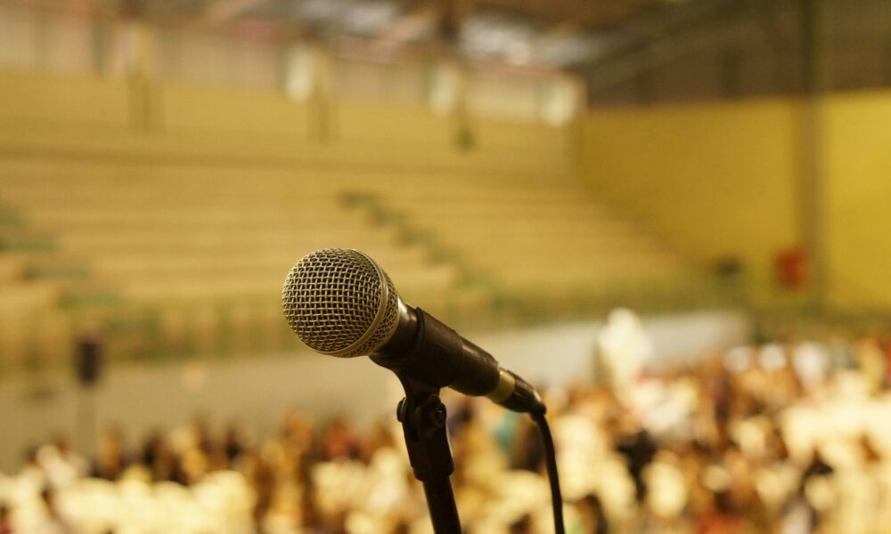 a microphone in the foreground, a blurred auditorium in the background