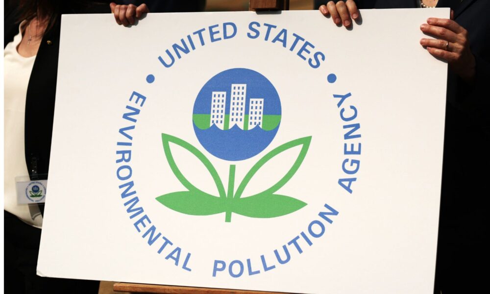 Activists' hands are pictured holding a sign with the logo of the U.S. Environmental Protection Agency, with text reading, "U.S. Environmental Pollution Agency," during a protest outside the headquarters of EPA in August.