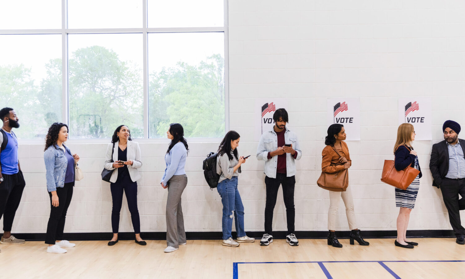 a diverse group of 9 people standing in line waiting to vote