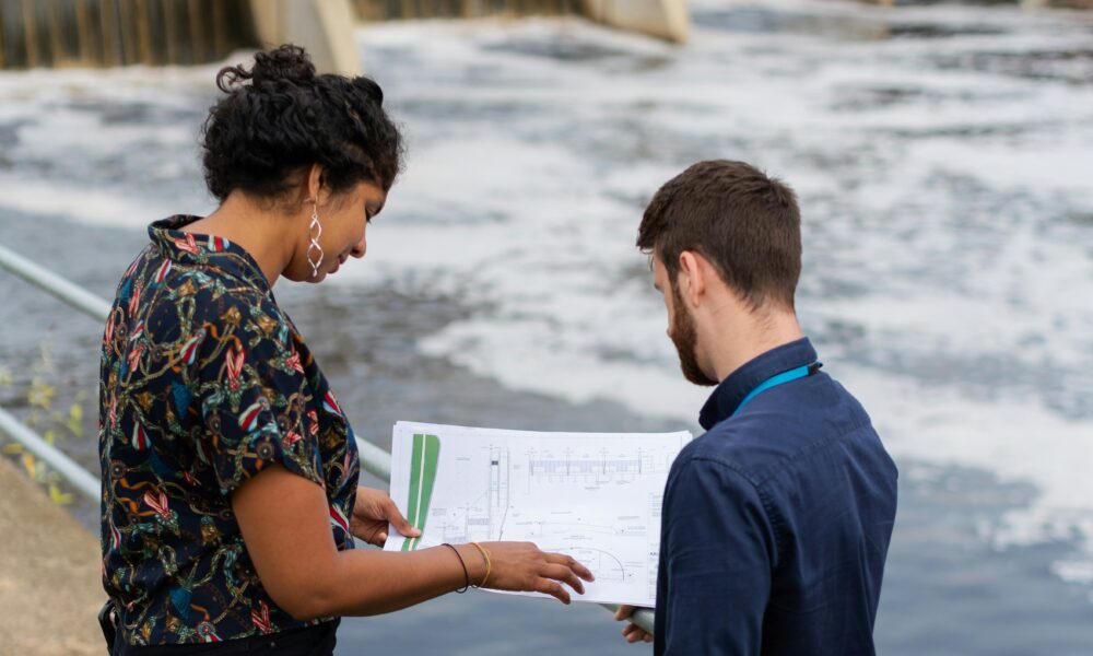 two people stand by a river looking at a chart
