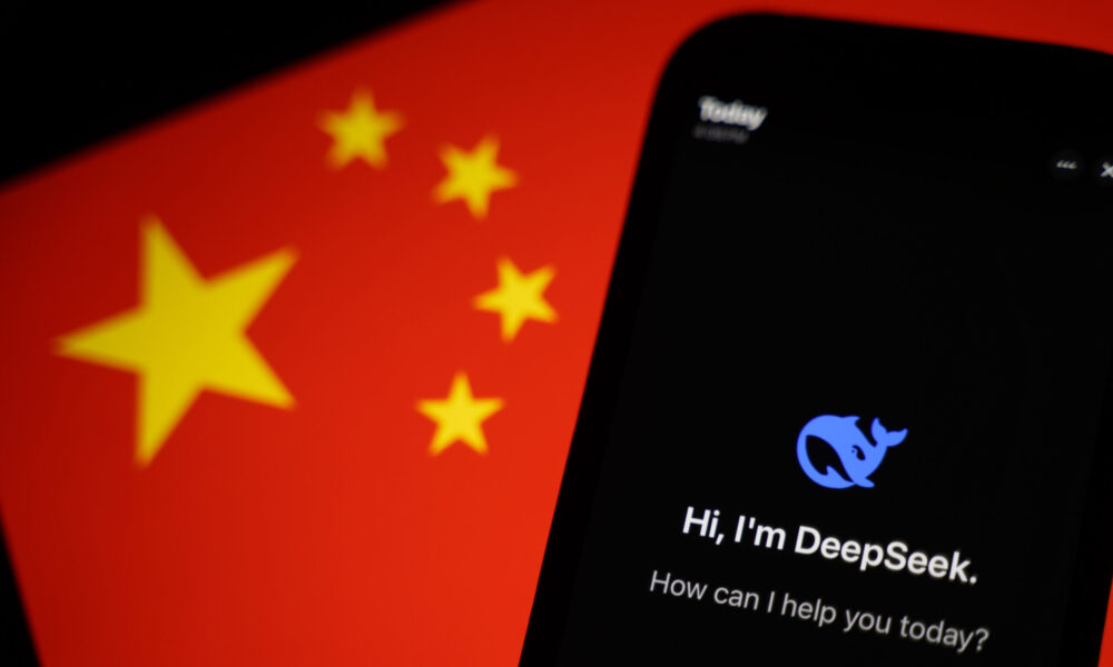 photo of a cell phone showing the DeepSeek logo and the words "Hi I'm DeepSeek, how can I help you today?" In the background is the flag of the People's Republic of China.