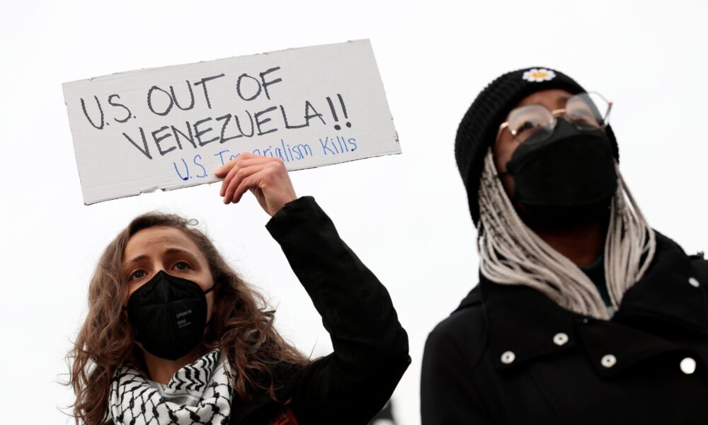 Protesters hold signs during a demonstration against U.S. military action in Venezuela on January 06, 2026 in Washington, DC.