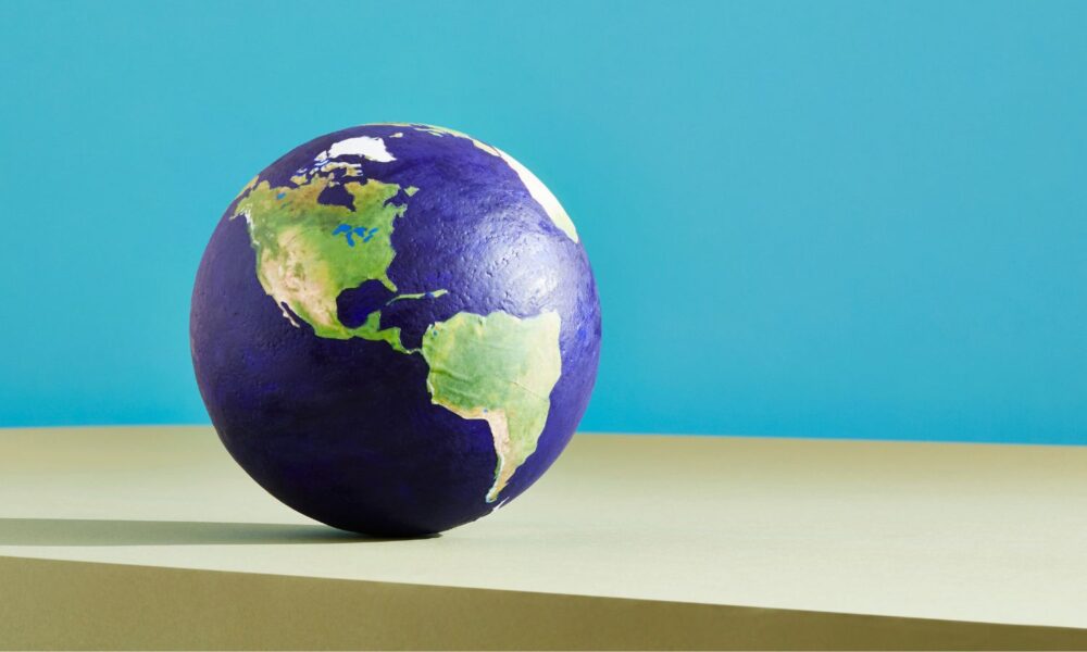 A globe centered on The Americas, sitting on a wooden table top with a blue background.