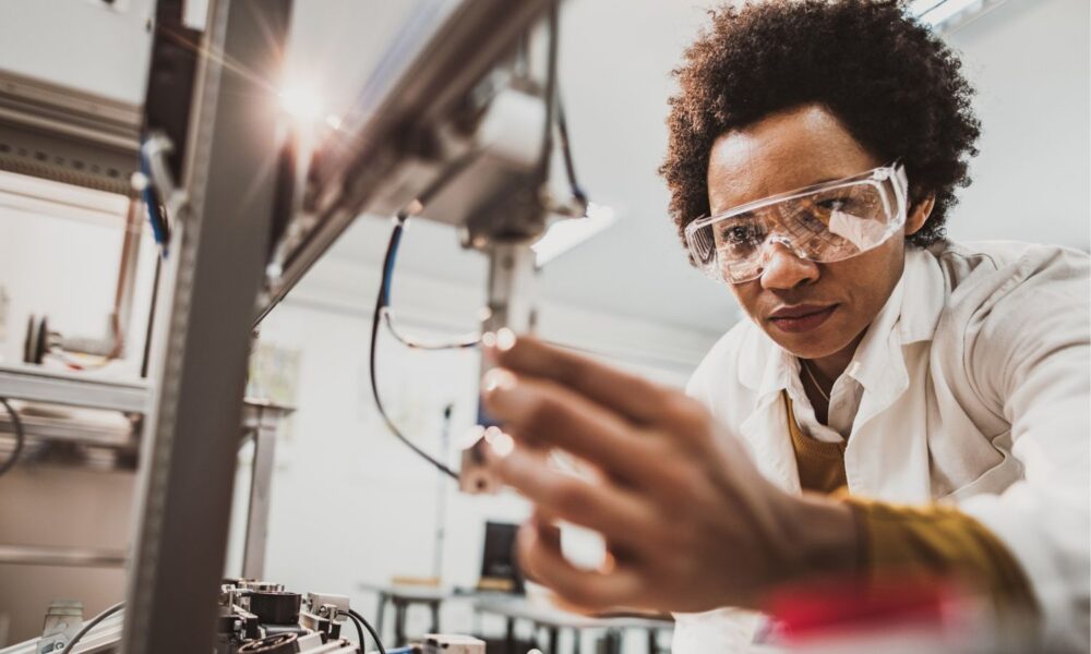 Low angle view of African American lab worker examining machine part while working in a lab.
