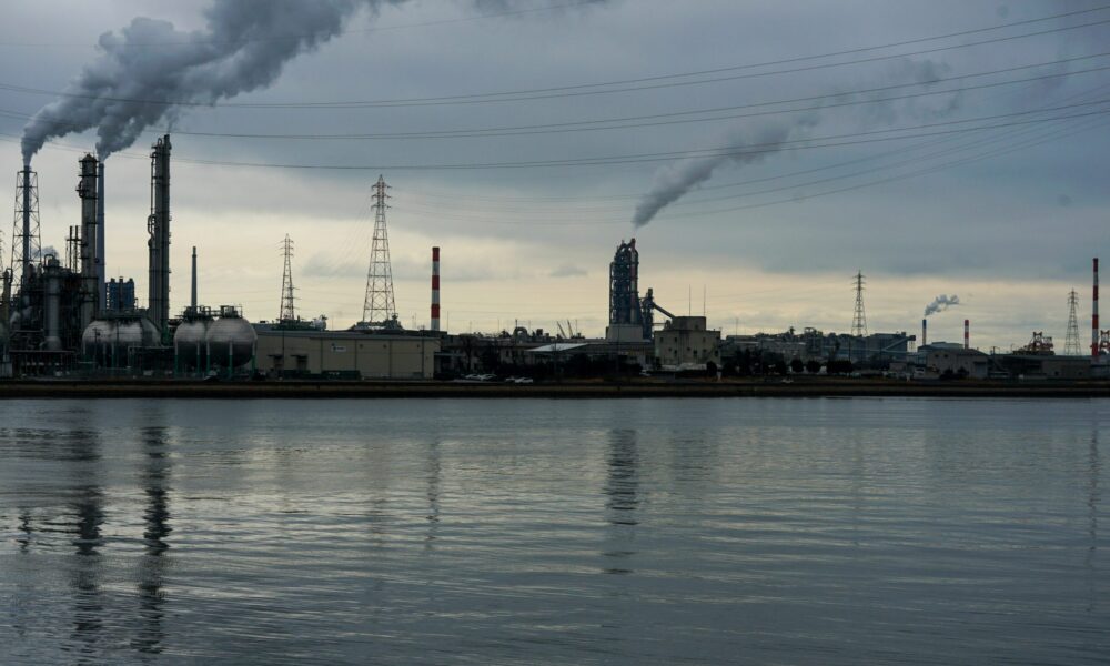 an industrial facility emitting smoke near a river