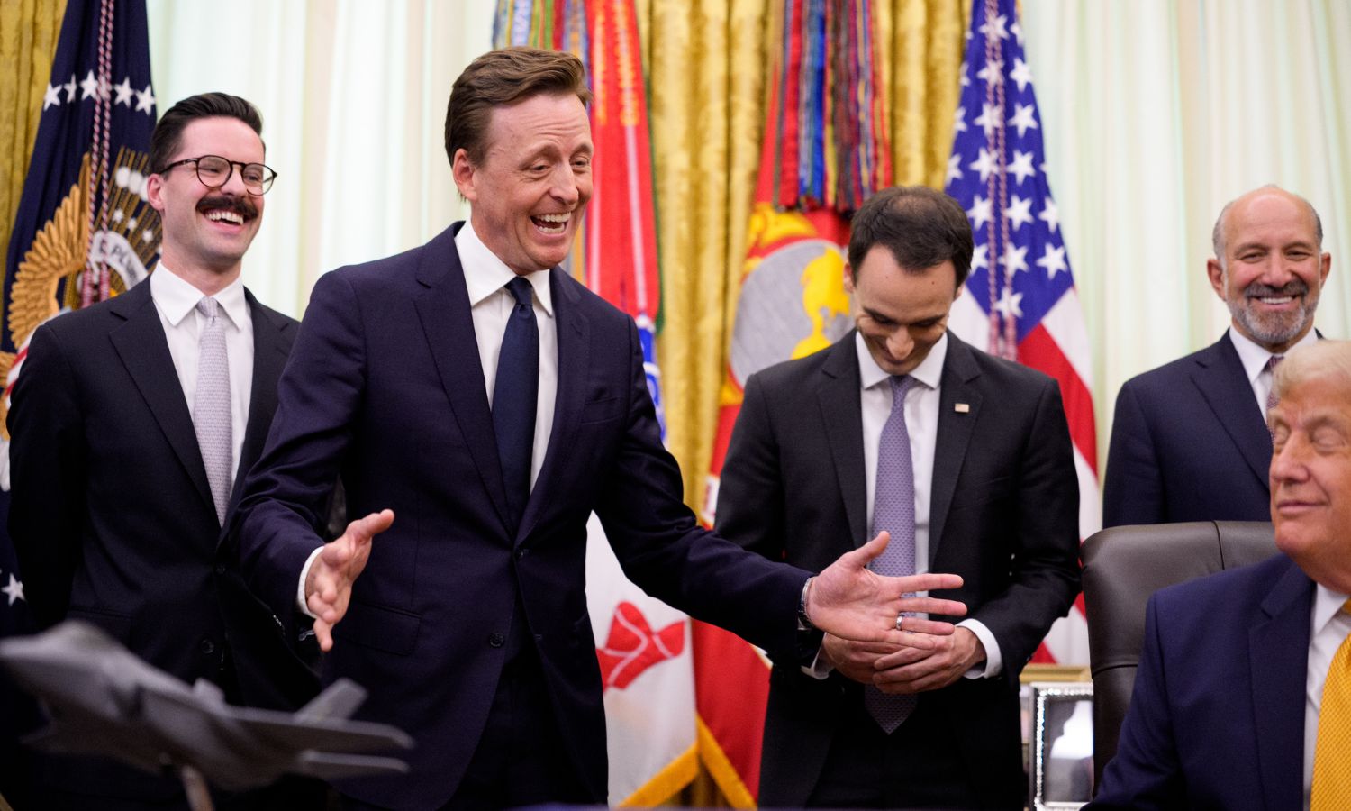 US National Cyber Director Sean Cairncross, US Chief Technology Officer Dr. Ethan Klein, White House Office of Science and Technology Policy Director Michael Kratsios, and Commerce Secretary Howard Lutnick are having a laugh in the Oval Office behind President Trump as he signs an executive order.