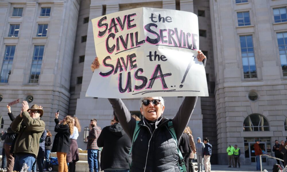 A woman holds a sign reading "save the civil service, save the USA" at the SAVE OUR DEMOCRACY Rally at USAID HQ at Ronald Reagan Building along 14th Street between Pennsylvania Avenue and Constitution Avenue, NW, Washington DC on Friday morning, 28 February 2025